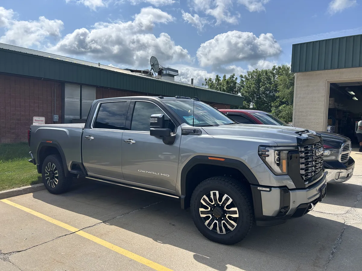 Finished: 2026 GMC Sierra 2500 HD Denali Ultimate for Lighthouse GMC with Avery Dennison Satin Black wrap film across the roof, upper cab, and pillars over the factory Sterling Metallic silver body — front three-quarter view.