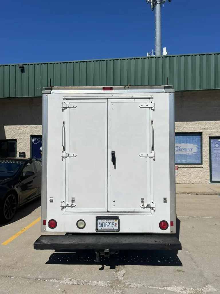 Rear doors of the service van before the wrap, showing the hinges and latch bars.