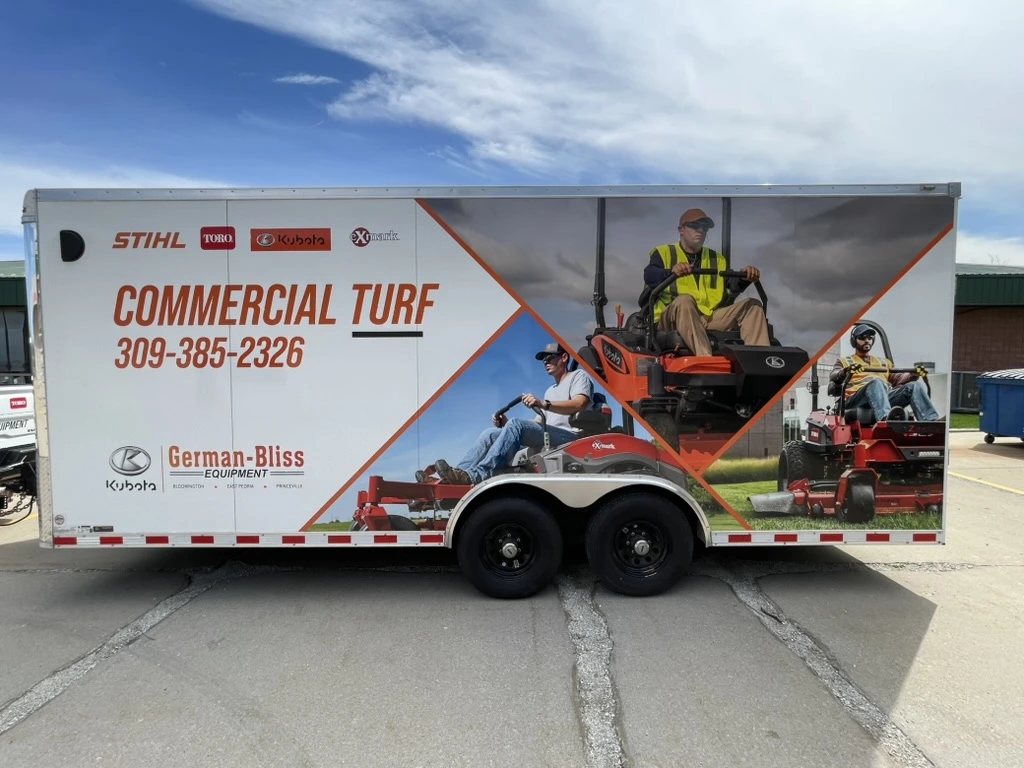 The German-Bliss Equipment trailer wrap, seen from the side. Turf equipment photos and dealer branding run the full length of the panel.