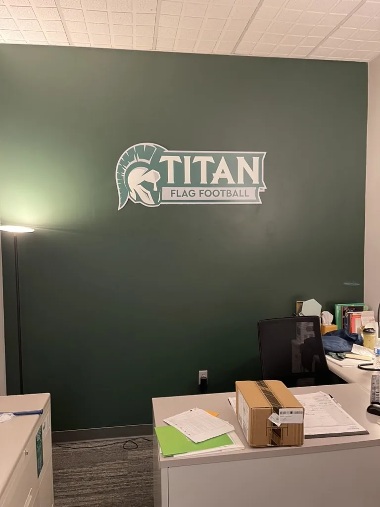 Cut-shape Titan Flag Football logo sign mounted in the coach's office at Illinois Wesleyan, Bloomington, IL.