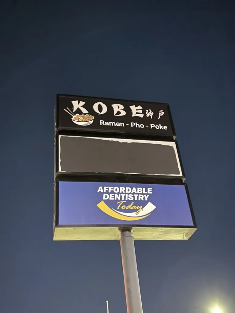 Illuminated Kobe Ramen Pho Poke pylon sign panel lit at night in Bloomington, IL.