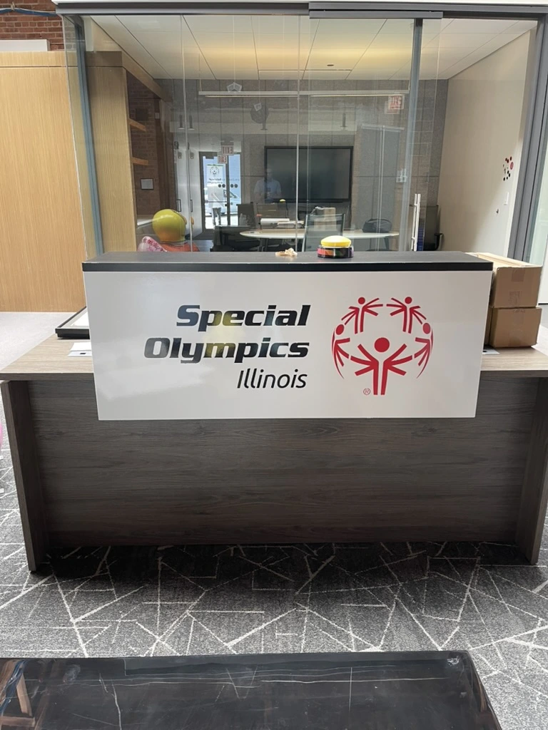 The Special Olympics Illinois reception sign in the Chicago office. The logo panel is fixed to the front of the desk.