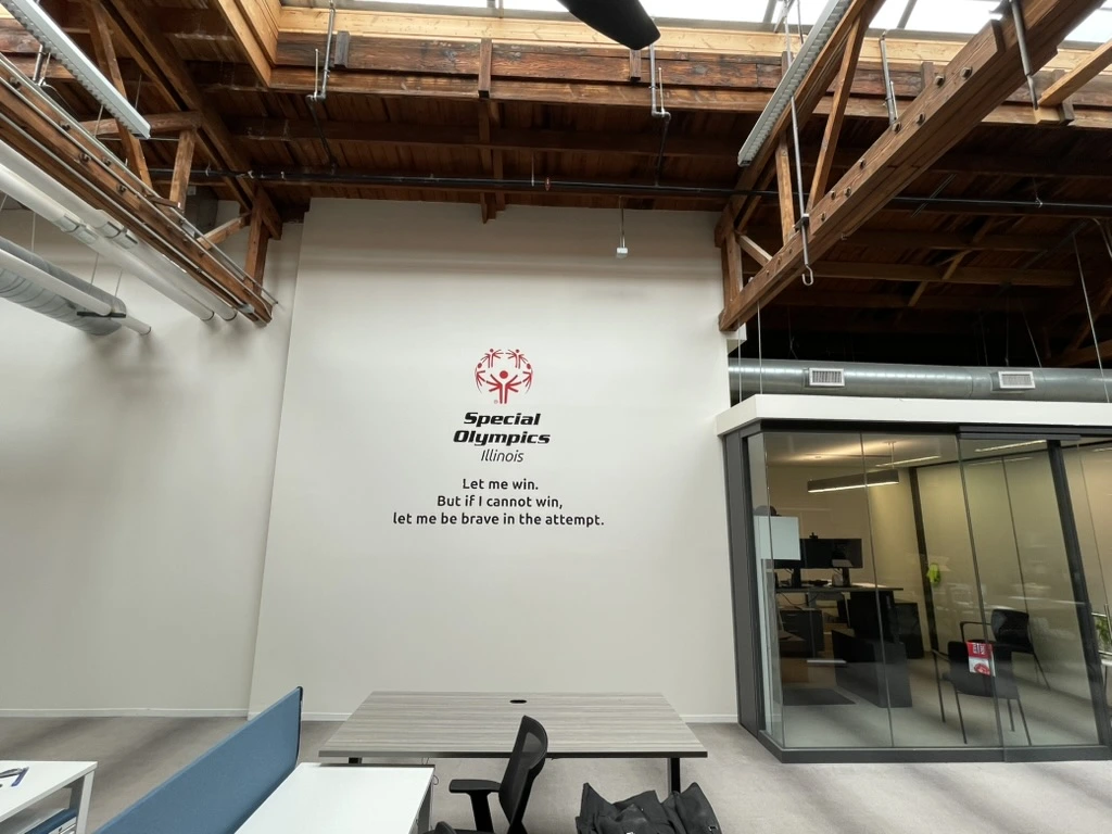 Wall graphics in the Special Olympics Illinois Chicago office. The logo sits above the athlete oath on a tall white wall.