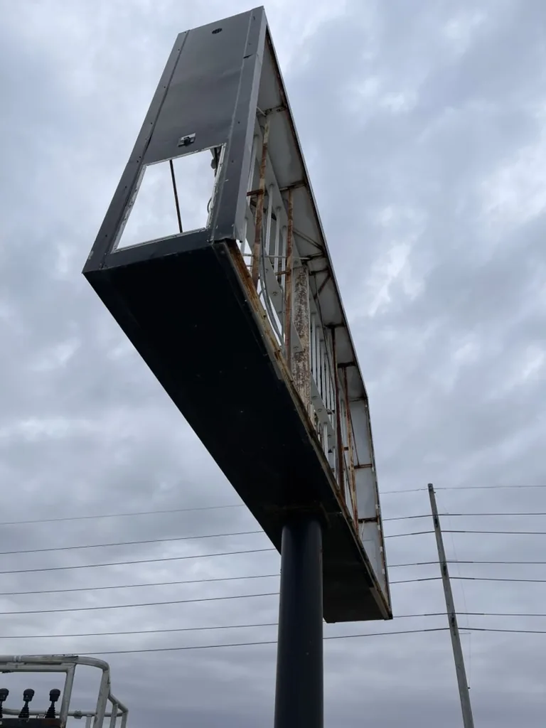 The stripped cabinet seen from a bucket truck, with rust on the frame and the old lamp channels still in place before it was repaired and repainted.