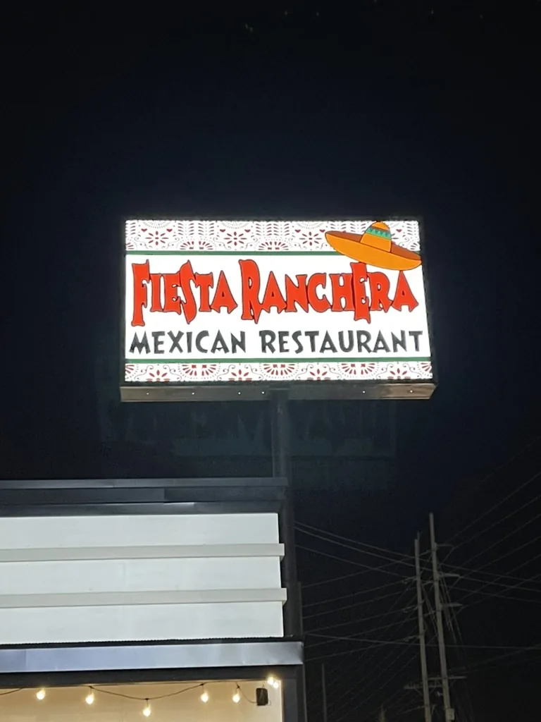 The finished sign lit at night on its freestanding pole, with the restaurant building below and to the left.