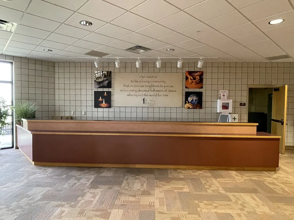 The long vision desk in its old mauve finish, below the painted vision statement panel on the lobby wall.