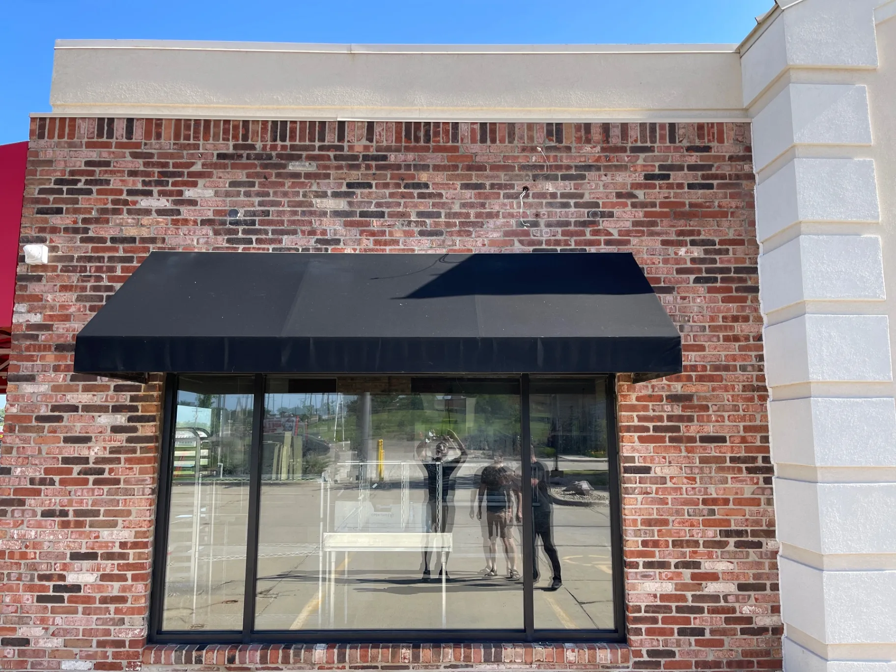 Kobe Ramen storefront before — bare brick facade with empty black awning above the window prior to channel letter install.
